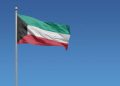 Flag of Kuwait in front of a clear blue sky