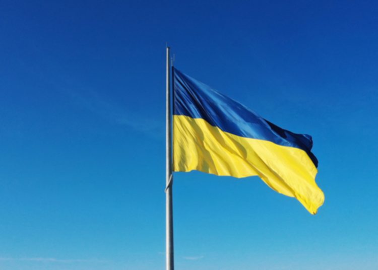 The flag of Ukraine develops on a flagpole against a background of clear sky