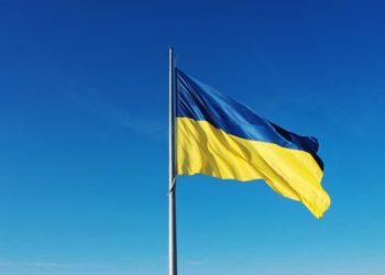 The flag of Ukraine develops on a flagpole against a background of clear sky